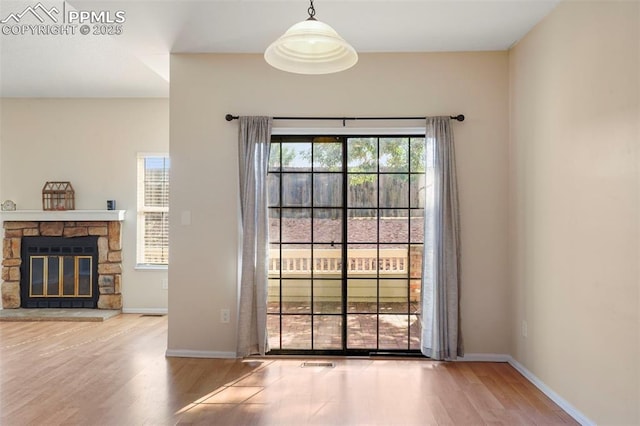 doorway to outside featuring wood-type flooring and a stone fireplace