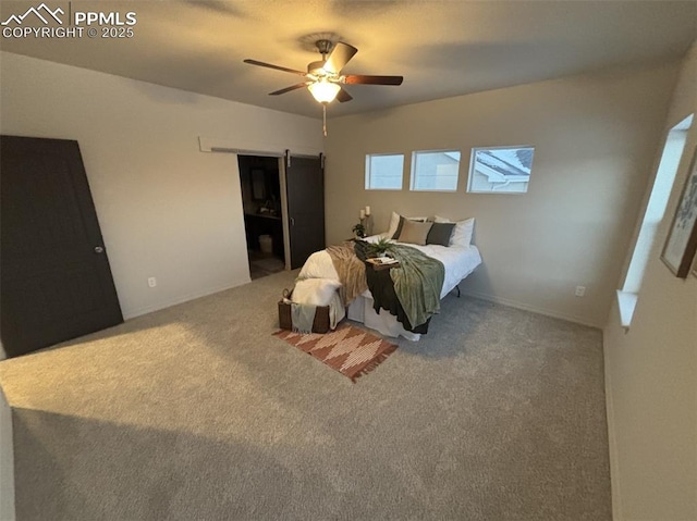 carpeted bedroom with a barn door and ceiling fan