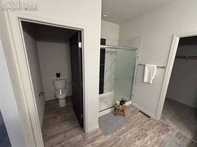 bathroom with hardwood / wood-style flooring, toilet, and walk in shower