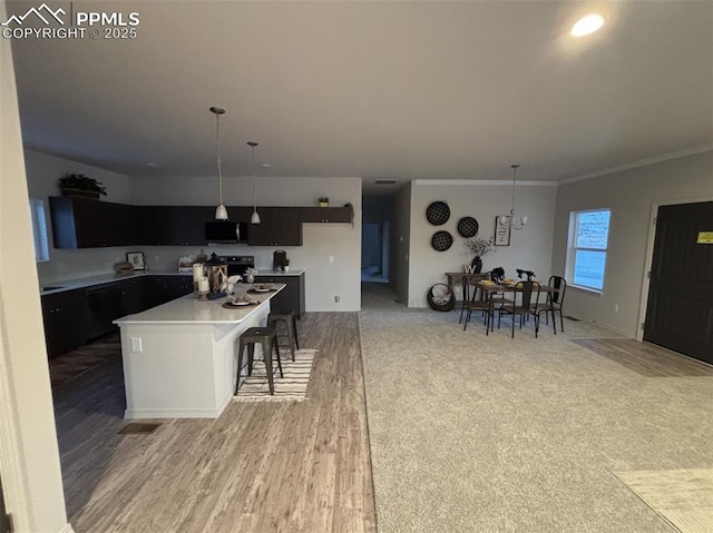 kitchen featuring pendant lighting, a breakfast bar, crown molding, hardwood / wood-style flooring, and a kitchen island