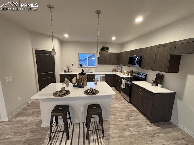 kitchen with a kitchen breakfast bar, a center island, decorative light fixtures, and appliances with stainless steel finishes