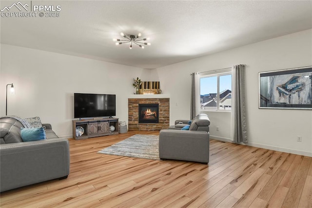 living room featuring a fireplace, light wood-type flooring, and a chandelier