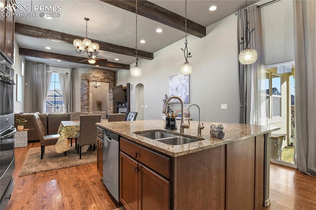 kitchen with sink, light stone counters, stainless steel appliances, and pendant lighting