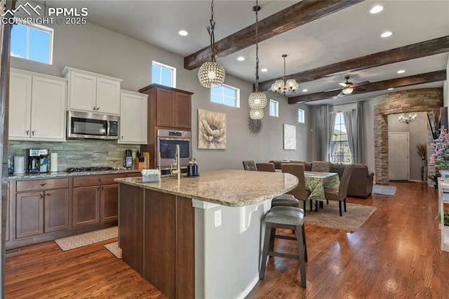 kitchen featuring pendant lighting, white cabinets, appliances with stainless steel finishes, a kitchen bar, and a kitchen island with sink