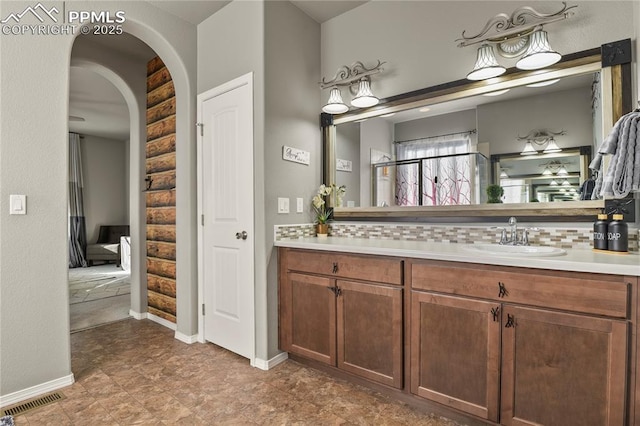 bathroom with rustic walls, vanity, and tasteful backsplash