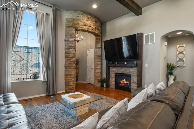 living room featuring beam ceiling, a notable chandelier, a fireplace, and hardwood / wood-style floors