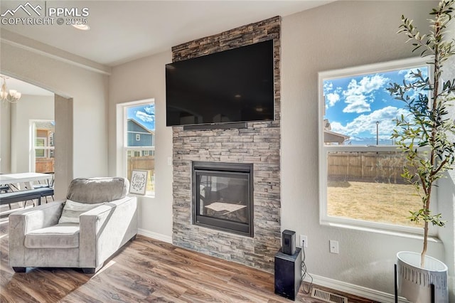 living room with a fireplace, wood-type flooring, and an inviting chandelier