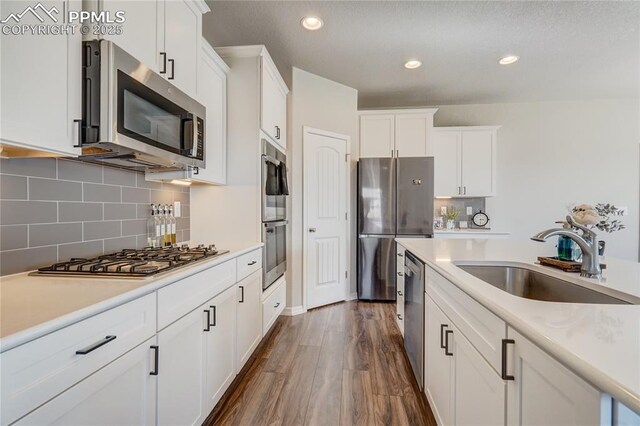 kitchen with white cabinets, sink, appliances with stainless steel finishes, tasteful backsplash, and dark hardwood / wood-style flooring