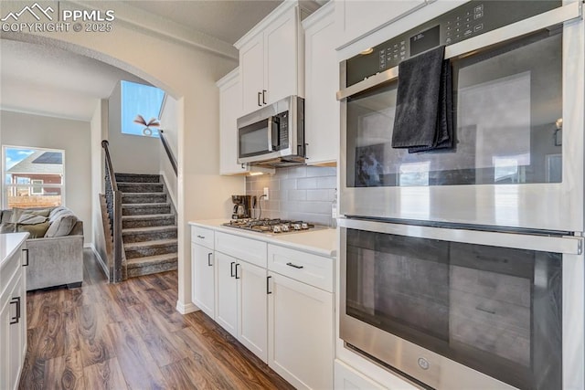 kitchen featuring tasteful backsplash, white cabinetry, dark hardwood / wood-style floors, and appliances with stainless steel finishes