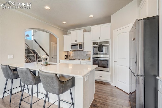 kitchen featuring a breakfast bar area, a center island with sink, white cabinets, and appliances with stainless steel finishes