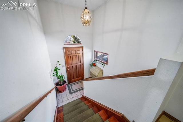 interior space with a high ceiling, stairway, a notable chandelier, and tile patterned floors