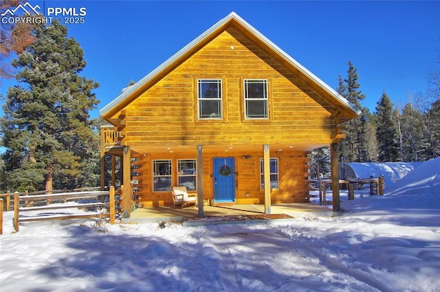 snow covered back of property with a porch