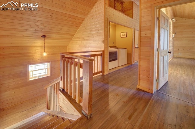 corridor with wood walls, wood-type flooring, vaulted ceiling, washing machine and dryer, and wood ceiling