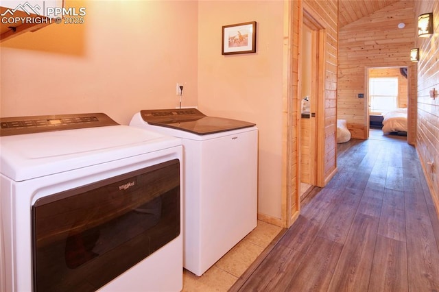 laundry room featuring wooden walls, washer and clothes dryer, and hardwood / wood-style floors