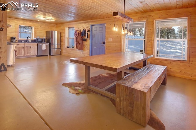 dining space with sink, wooden walls, and wood ceiling