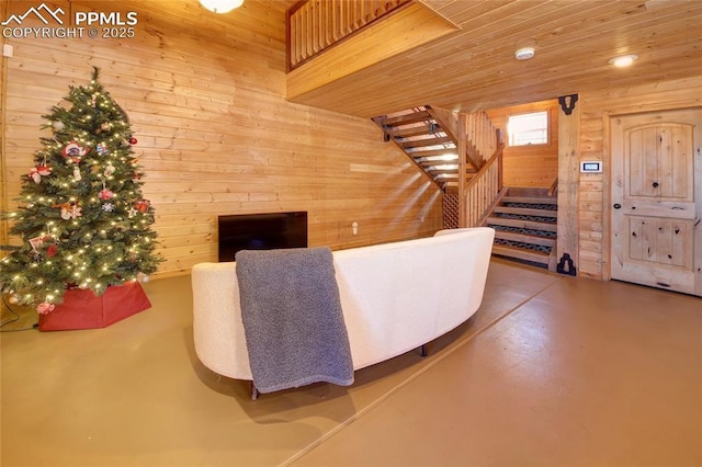 living room featuring wooden walls, concrete floors, and wooden ceiling