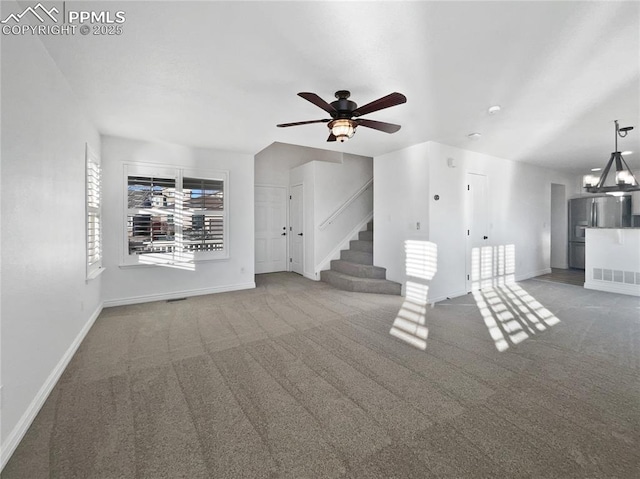 unfurnished living room with carpet and ceiling fan with notable chandelier