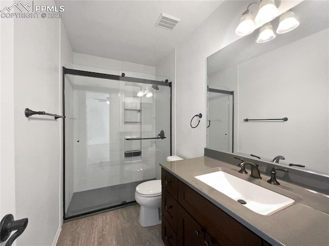 7707 Orange Sunset Dr, Colorado Springs, CO 80922 - bathroom featuring hardwood / wood-style flooring, vanity, toilet, and an enclosed shower