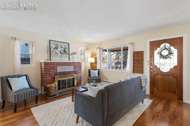 living room with a brick fireplace and wood-type flooring