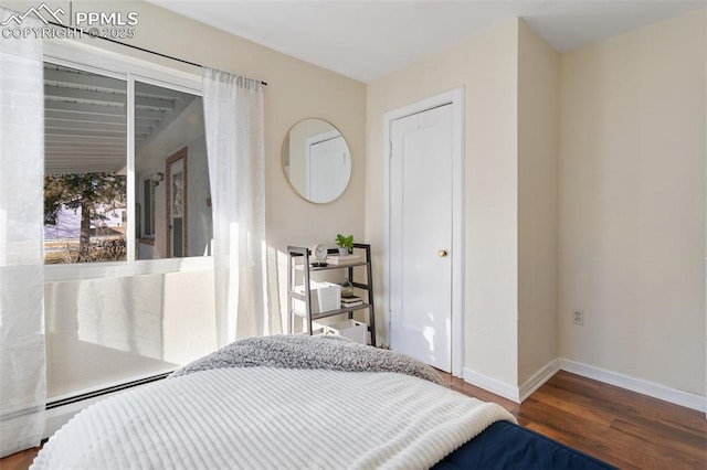 bedroom with baseboard heating and hardwood / wood-style floors