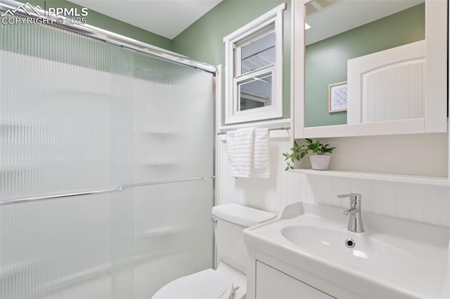 bathroom with toilet, an enclosed shower, and vanity