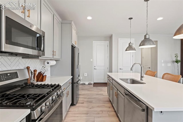 kitchen featuring pendant lighting, appliances with stainless steel finishes, sink, backsplash, and a center island with sink