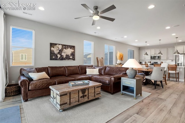 living room with light wood-type flooring, ceiling fan, and a wealth of natural light