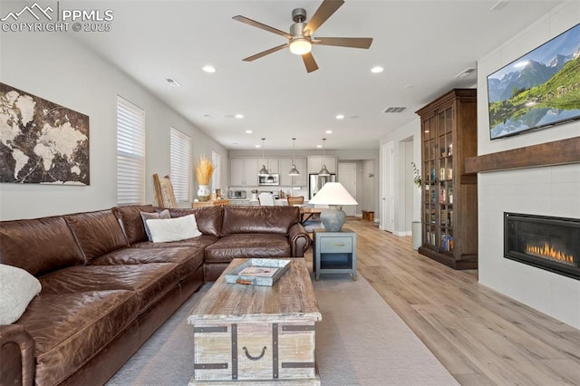 living room with a fireplace, light hardwood / wood-style floors, and ceiling fan