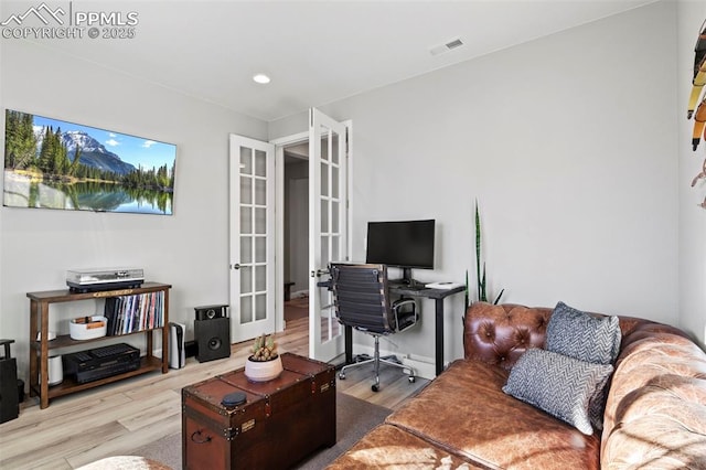 office with light hardwood / wood-style floors and french doors