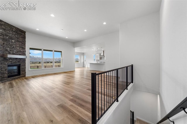 staircase featuring hardwood / wood-style flooring and a stone fireplace