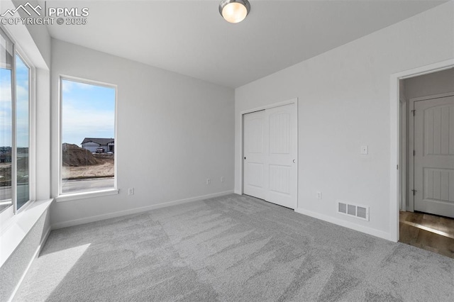 unfurnished bedroom featuring light colored carpet and a closet