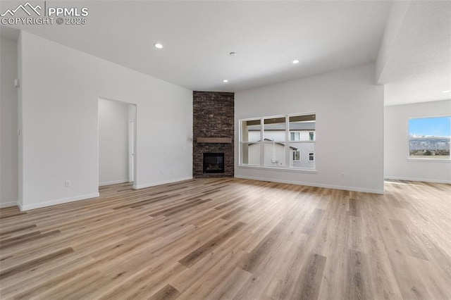 unfurnished living room featuring light hardwood / wood-style flooring and a stone fireplace