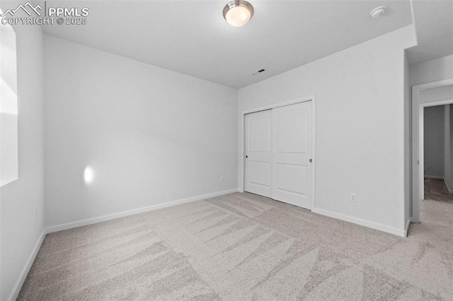 unfurnished bedroom featuring light carpet and a closet