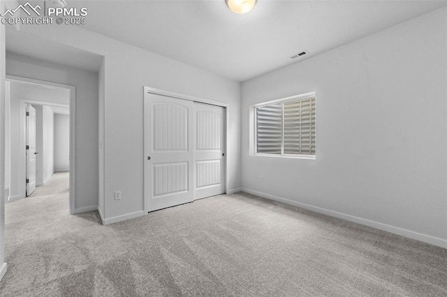 unfurnished bedroom with light colored carpet and a closet