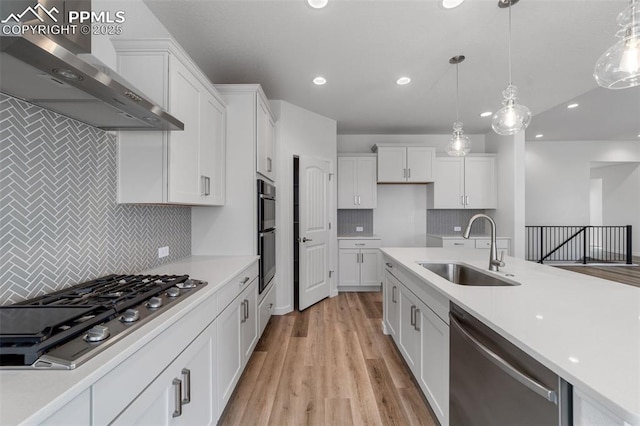 kitchen featuring appliances with stainless steel finishes, sink, decorative light fixtures, and wall chimney range hood