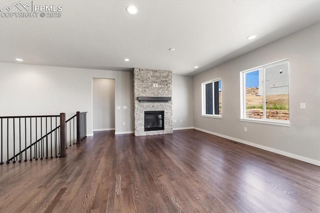 unfurnished living room featuring dark hardwood / wood-style flooring and a stone fireplace