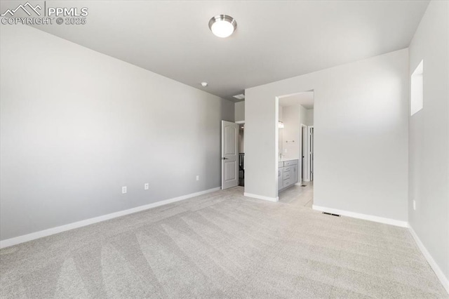 unfurnished bedroom featuring light carpet and connected bathroom