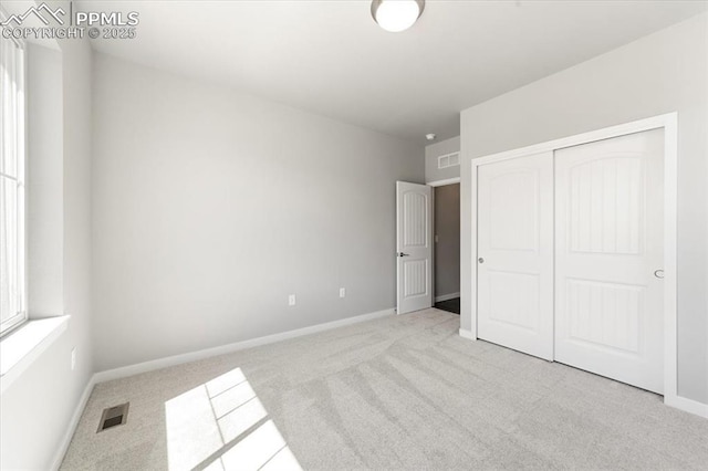 unfurnished bedroom with light carpet and a closet