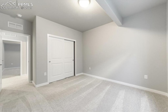 unfurnished bedroom with beam ceiling and light carpet