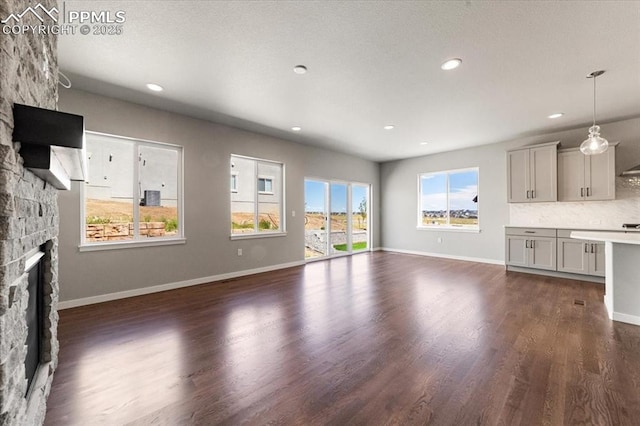 unfurnished living room featuring dark hardwood / wood-style floors and a stone fireplace