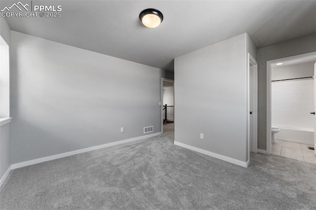 unfurnished bedroom featuring connected bathroom and light colored carpet