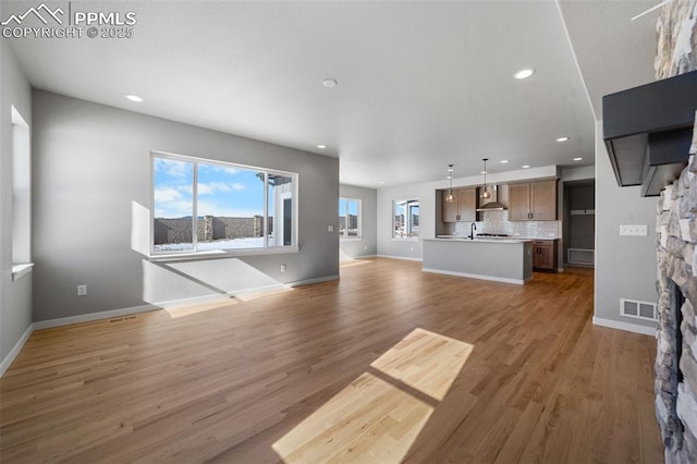 unfurnished living room with dark hardwood / wood-style floors, a stone fireplace, and plenty of natural light