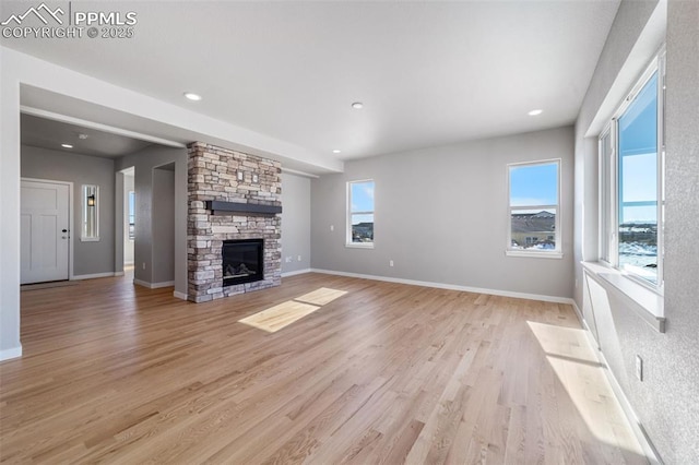 unfurnished living room featuring a fireplace, light hardwood / wood-style floors, and plenty of natural light