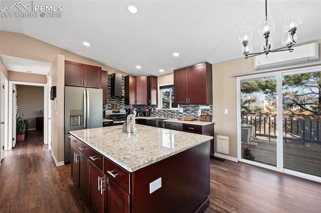 kitchen with vaulted ceiling, wall chimney range hood, a kitchen island, pendant lighting, and stainless steel appliances