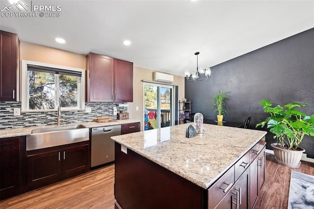 kitchen with a notable chandelier, dishwasher, a kitchen island, pendant lighting, and sink