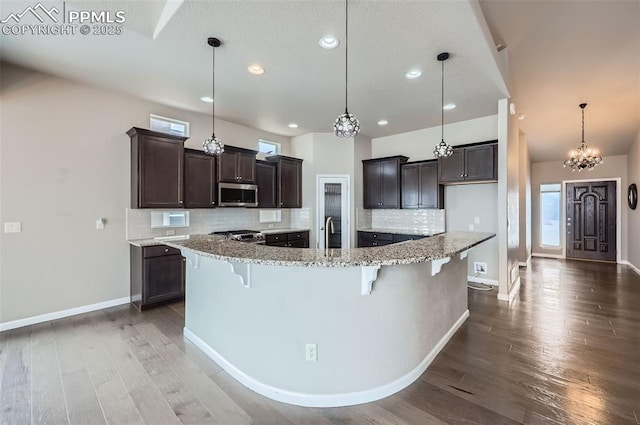 kitchen featuring stainless steel appliances, tasteful backsplash, a breakfast bar area, light stone countertops, and pendant lighting