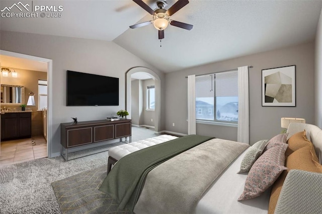 bedroom featuring ensuite bath, ceiling fan, vaulted ceiling, and light colored carpet