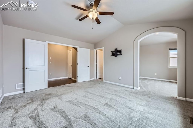 unfurnished bedroom featuring ceiling fan, vaulted ceiling, and carpet flooring