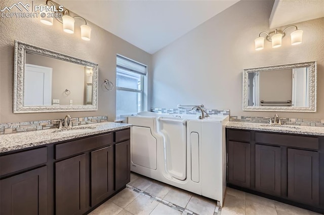 bathroom with vanity, tile patterned floors, vaulted ceiling, and a bath