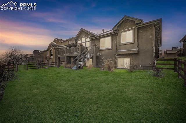 back house at dusk featuring a yard and a wooden deck